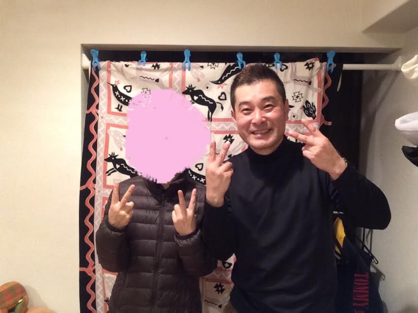 顔を写真加工で隠したダウンジャケットを着た女性のお客様と前田歩の笑顔のツーショット写真