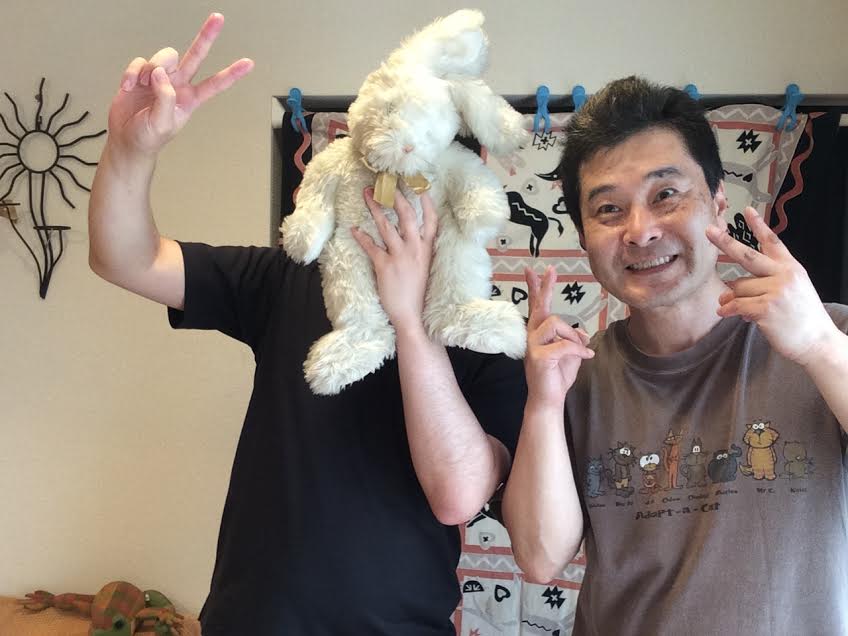 顔を兎のぬいぐるみで隠した男性のお客様と前田歩の笑顔のツーショット写真