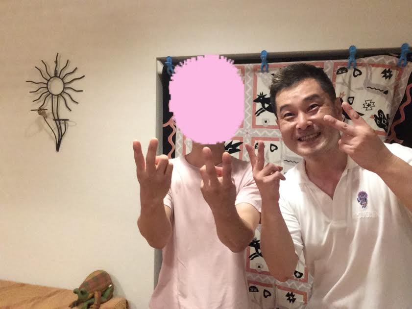 肩こり・首こり・背中の張りが改善してお喜びの男性のお客様と前田歩の笑顔のツーショット