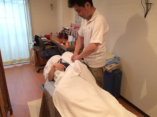 ボディケア前田にて女性のお客様の左腕を横向きで整体マッサージ施術する前田歩