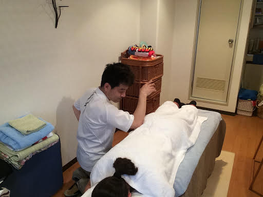 前田歩がうつ伏せの女性のお客様へ肘で臀部への整体マッサージ施術をしているところ